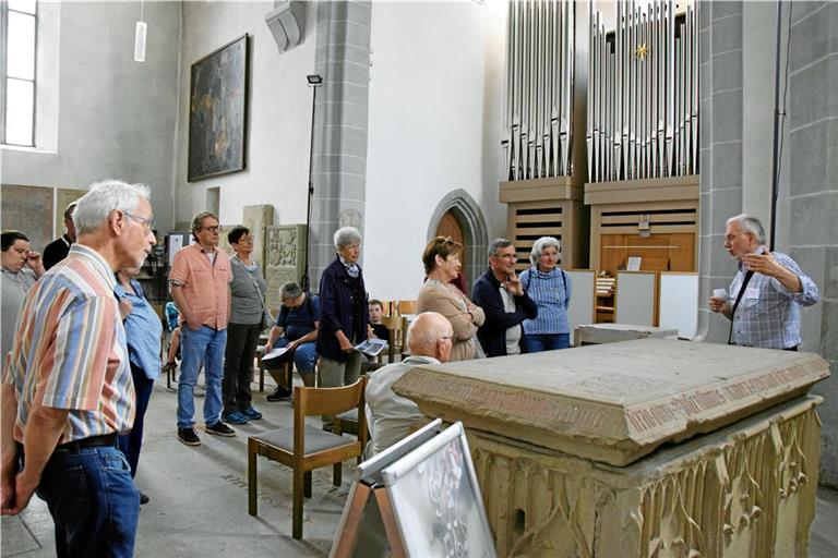 Kirchenführer Manfred Schurr (rechts) vor dem Erinnerungsgrabmal für Kaiser Ludwig den Frommen und die Gruppe in der Vierung der Stadtkirche Murrhardt. Sie hat sich über die Jahrhunderte merklich verändert. Foto: Elisabeth Klaper