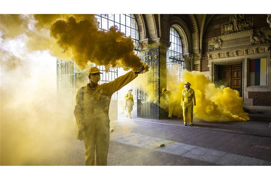 Klimaaktivisten von Extinction Rebellion blockieren bei einer Protestaktion den Durchgang zum Rijksmuseum in Amsterdam. Dabei wird viel gelbe Pyrotechnik eingesetzt.