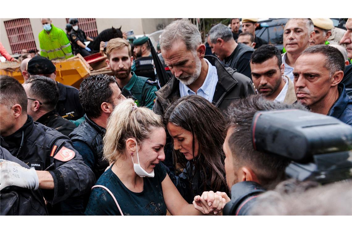 König Felipe VI. (M) und Königin Letizia (M, unten) bei ihrem Besuch in einem von den Überschwemmungen betroffenen Gebiet. Am Dienstag will Felipe wieder ins Katastrophengebiet reisen. (Archivbild)