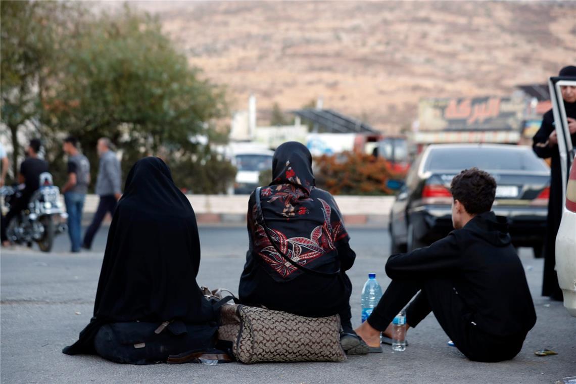 Libanesen, die vor dem israelischen Bombardement fliehen, sitzen auf dem Boden, nachdem sie den syrisch-libanesischen Grenzübergang in Jdaidet Yabous überquert haben.