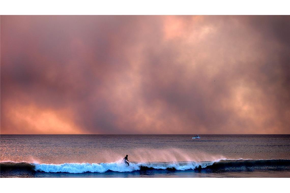 Manchen lassen die Waldbrände in auch Kalifornien kalt: Dieser Surfer reitet auf einer Welle, während Rauch den Himmel verdunkelt.