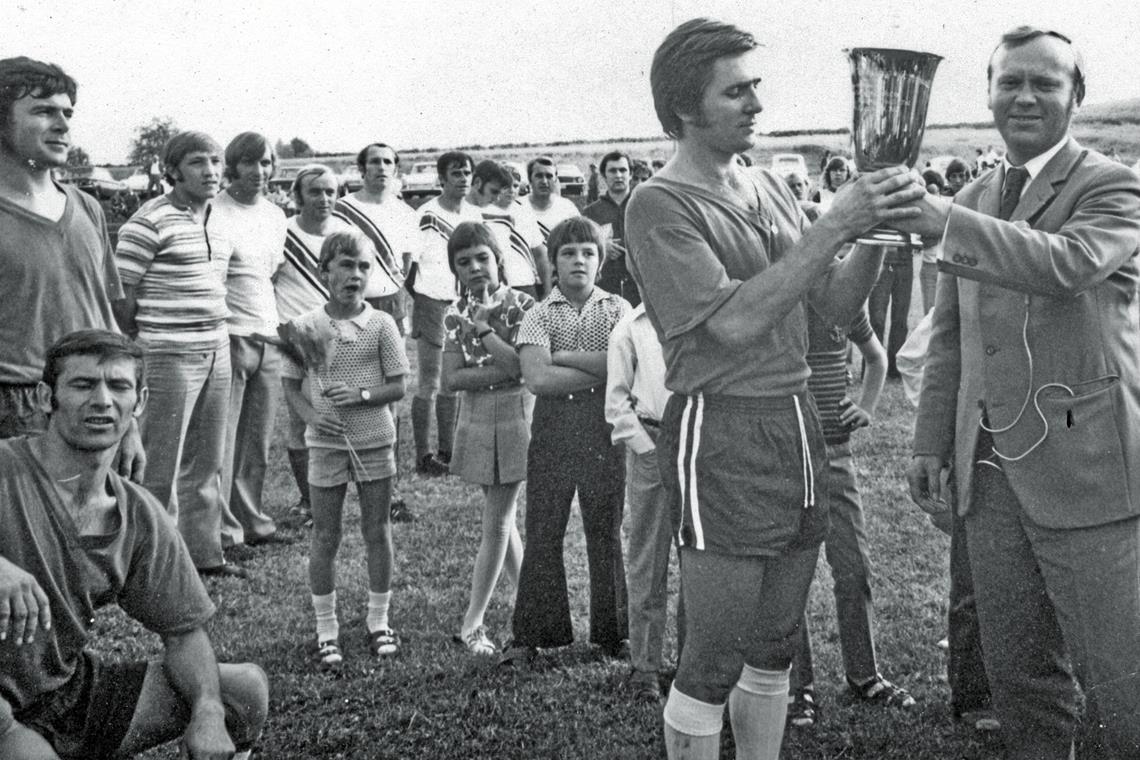 Marschierten mit Lippoldsweiler binnen zehn Jahren von der C-Klasse in die 2. Amateurliga: Hans Herb (links), Helmut Hermann (unten) und Kapitän Bernd Schneider, dem der damalige Auenwalder Bürgermeister Walter Schmitt den Pokal für den Sieg beim Weissacher Tal-Turnier überreicht. Foto: privat: