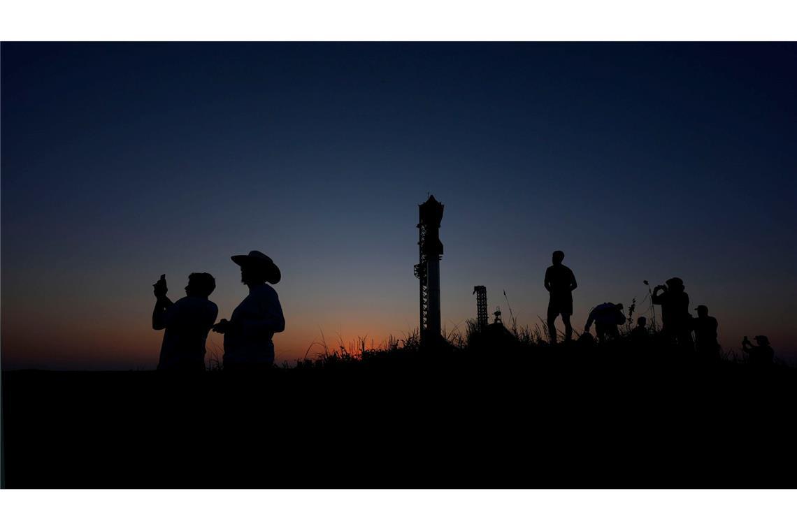 Menschen fotografieren den Sonnenuntergang hinter der Rakete Starship von SpaceX.