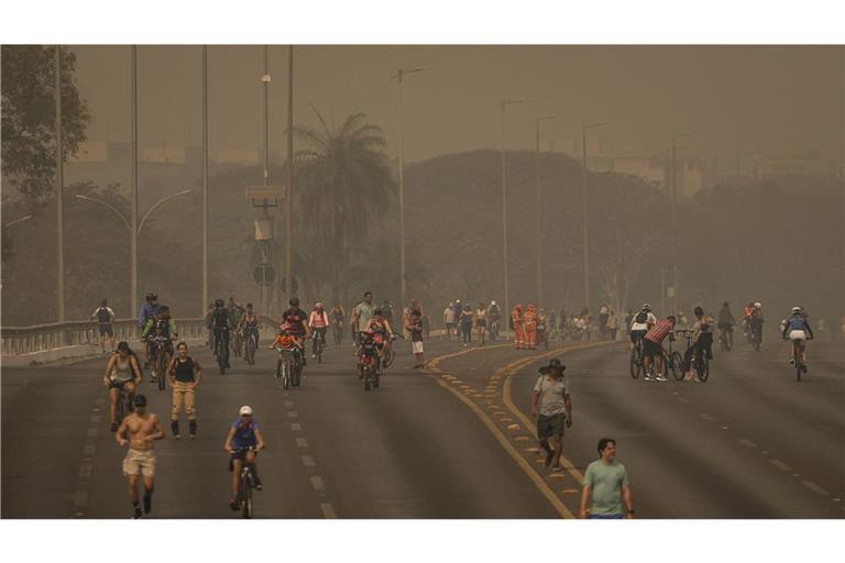 Menschen treiben Sport an einer gesperrten Straße, als dichter Rauch aufgrund schwerer Brände über die Stadt zieht.