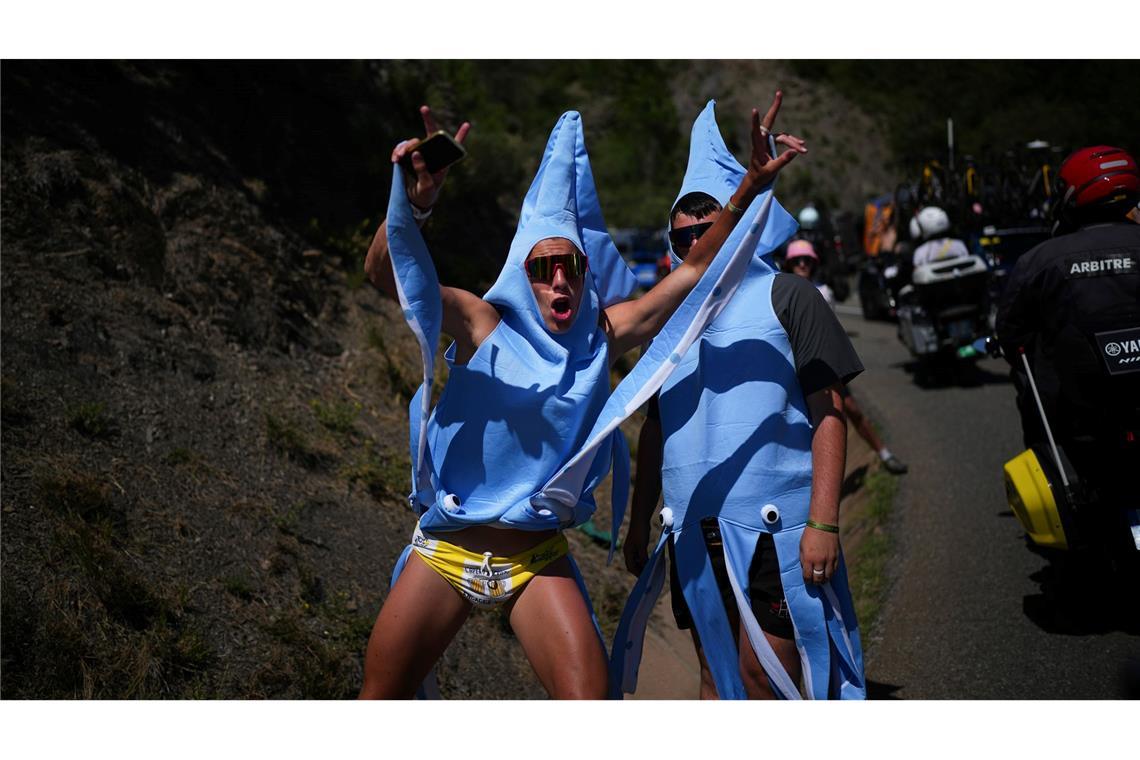 Mit ausgestreckten Armen feuern zwei verkleidete Fans das Feld auf der 18. Etappe bei der Tour de France an.