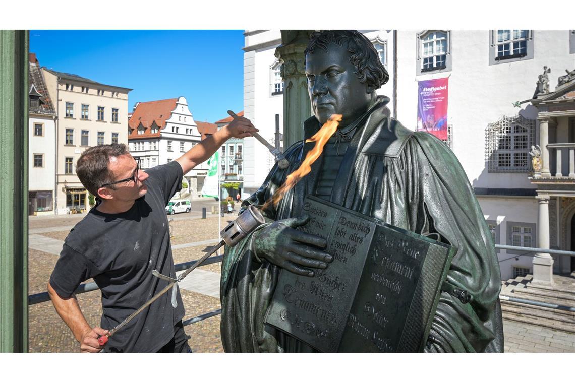 Mit Feuer aufgehübscht: Metallrestaurator Oliver Behr bringt auf das Luther-Denkmal auf dem Marktplatz von Wittenberg ein Spezialschutzwachs auf.