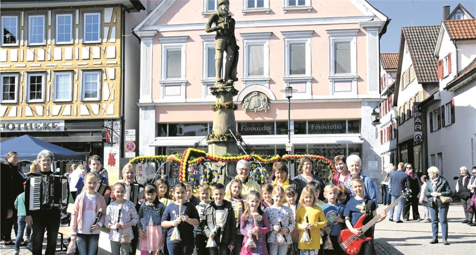 MURRHARDT (eke). Die Murrhardter Landfrauen haben den Marktbrunnen in einen Osterbrunnen verwandelt. Über der Bepflanzung aus Frühlingsblumen und erstem Frühlingsgrün erhebt sich eine Krone und Osterpalmen aus gefärbten Eiern und Girlanden mit Filzblüten zieren die Säule, auf der Herzog Christoph steht. Schönstes Frühlingswetter lockte eine große Besucherschar zur Einweihungsfeier. „Der Osterbrunnen symbolisiert den Beginn des Frühlings und die Bedeutung des Wassers als lebensnotwendiges Element. Dieses alte Landfrauen-Brauchtum stammt ursprünglich aus der Fränkischen Schweiz“, erklärte Monika Bay vom Vorstandsteam. Sie trug das heitere Gedicht „Osterfreude“ vor, dankte allen Helferinnen sowie Hanne Schweizer und ihrem Team für die Organisation. „Die Landfrauen haben einen besonderen Osterbrunnen mit viel mehr Mühe gestaltet“, hob Bürgermeister Armin Mößner hervor. Der trockene Sommer 2018 habe die Bedeutung des Wassers gezeigt: „Es ist eines der wichtigsten Güter, die wir haben.“ Der Spielkreis der Musikschule Schwäbischer Wald/Limpurger Land umrahmte die Feier: Unter Birgit Heims Regie spielten Kinder mit Flöten, Akkordeons und einer E-Bassgitarre Frühlings- und Volksweisen. Zudem boten die Landfrauen selbst gebackene Spezialitäten und Osterkränze an. Foto: E. Klaper