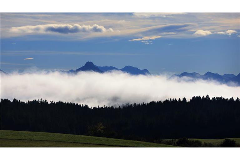 Nebel lichtet sich im Alpenvorland vor den Berggipfeln.