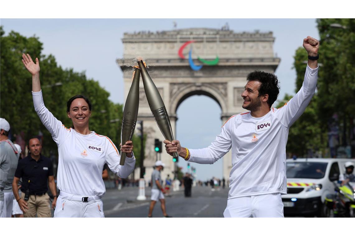 Olympia-Countdown: Fackelträger Nina Metayer, eine französische Konditorin, und Amir, ein französisch-israelischer Sänger, halten die olympische Fackel auf der Avenue des Champs-Elysees.