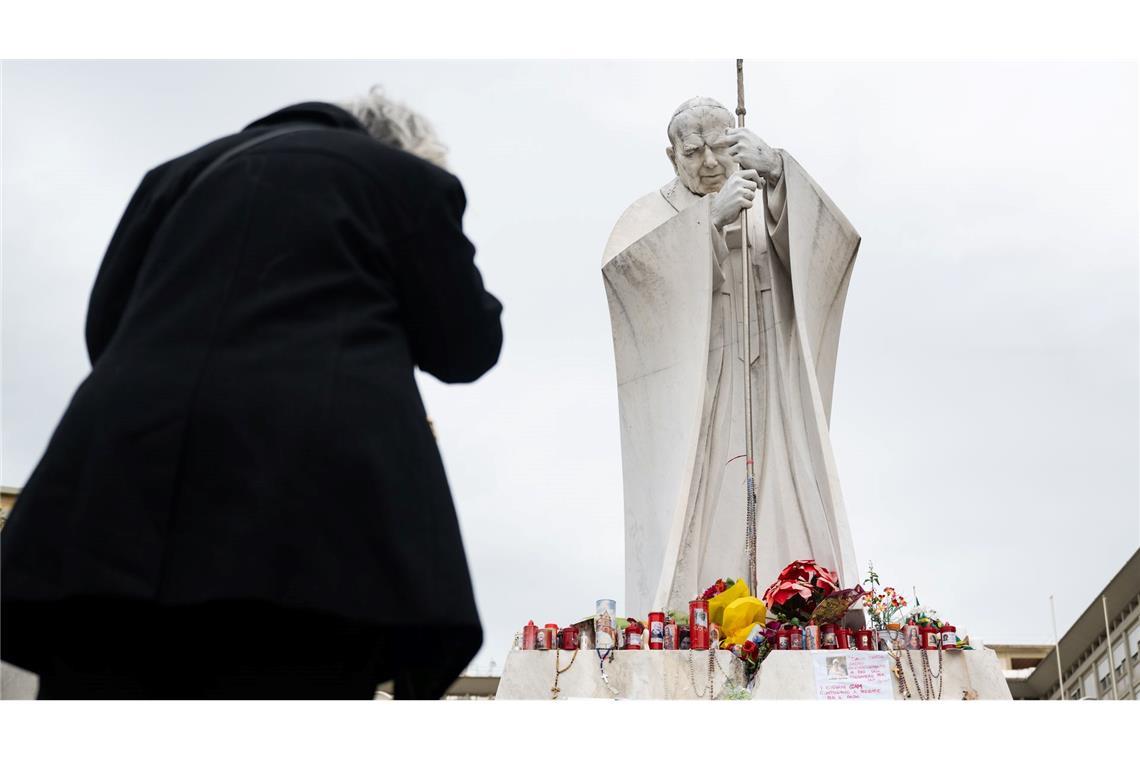 Papst Franziskus im Krankenhaus: eine Frau betet unter der Statue von Papst Johannes Paul II. vor der Poliklinik Agostino Gemelli.