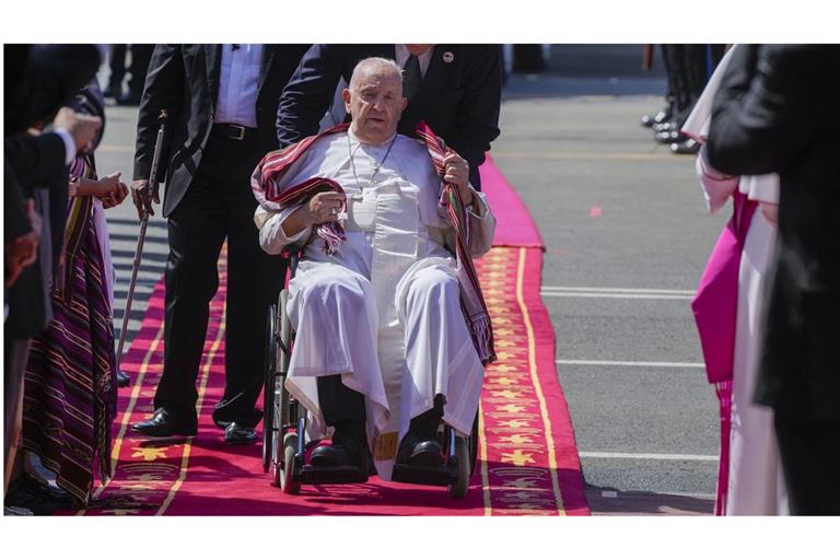 Papst Franziskus trägt ein Tais, das traditionelle Tuch Osttimors, das ihm am 9. September 2024 nach seiner Ankunft auf dem Presidente Nicolau Lobato International Airport in Dili, Osttimor, überreicht wurde.