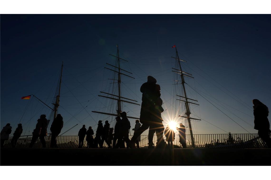 Passanten genießen das sonnige Wetter auf der Jan-Fedder-Promenade im Hamburger Hafen.