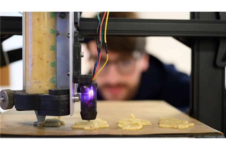 Plätzchen aus dem 3D-Drucker: Ein wissenschaftlicher Mitarbeiter der Professur Additive Fertigung an der TU Bergakademie Freiberg betrachtet die Herstellung von Plätzchen mit einem mobilen 3D-Drucker.