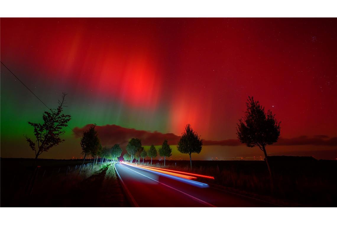 Polarlichter leuchten am Nachthimmel über einer Straße im östlichen Brandenburg.