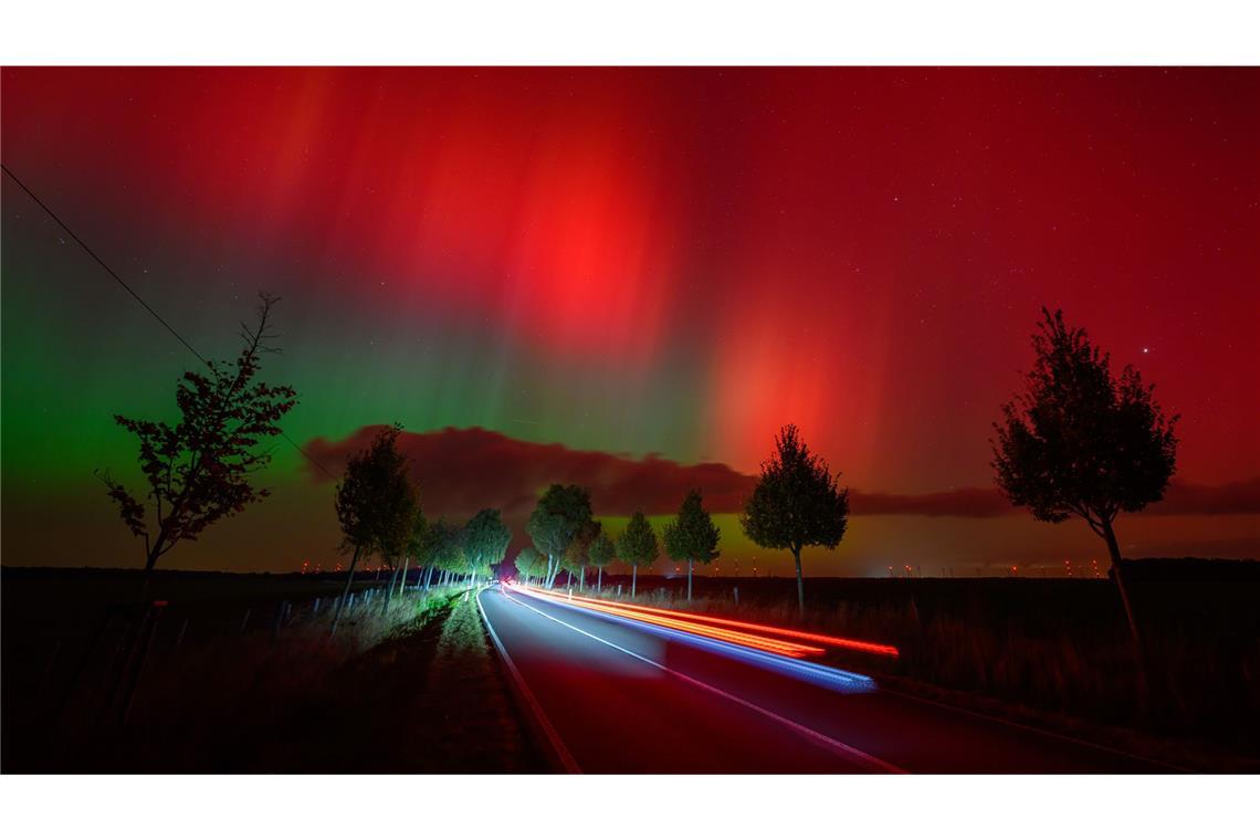 Polarlichter leuchten am Nachthimmel über einer Straße im östlichen Brandenburg.