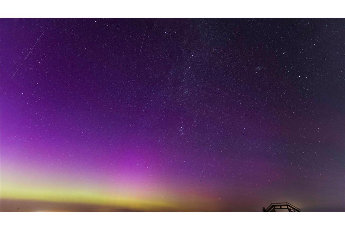 Polarlichter und eine Sternschnuppe der Perseiden sind bei sternenklarer Nacht über der Ostsee zu sehen.