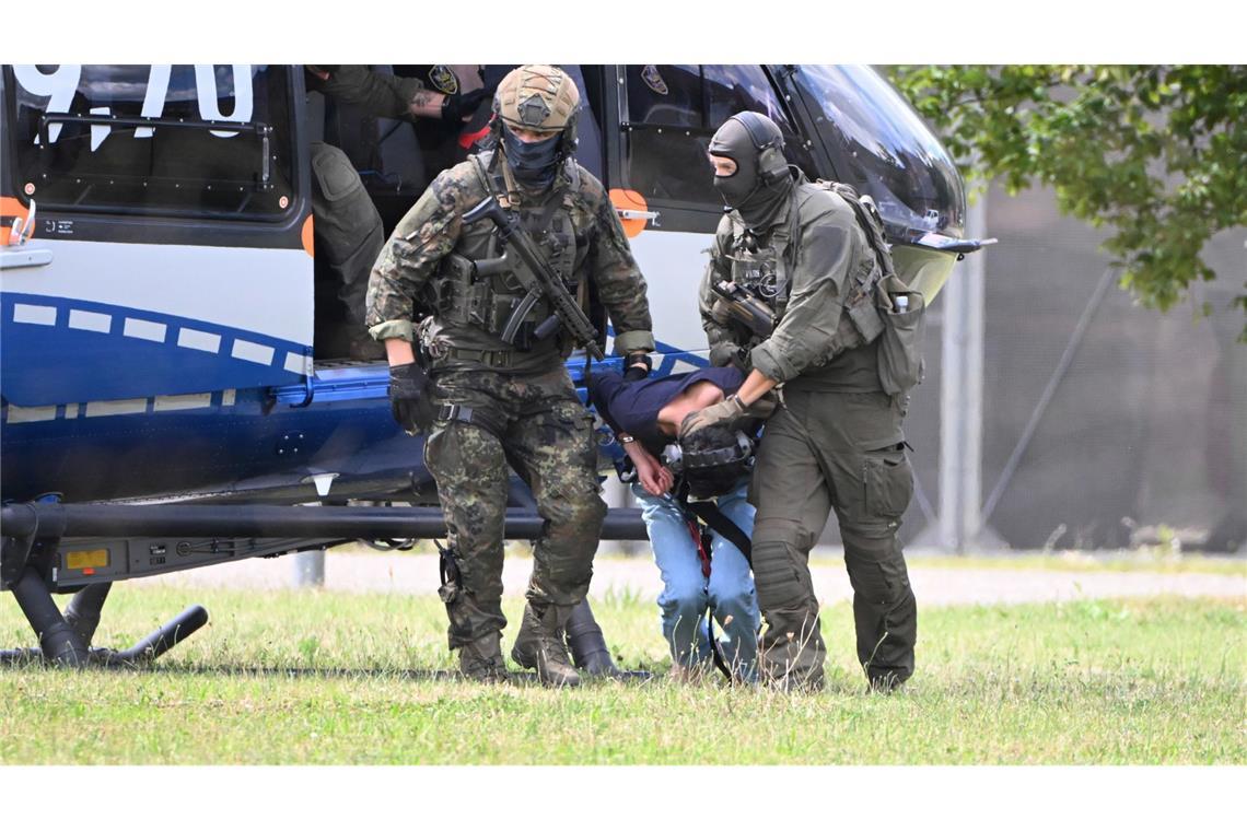 Polizisten bringen den Tatverdächtigen zu einer Wagen-Kolonne, die ihn zum BGH fährt.