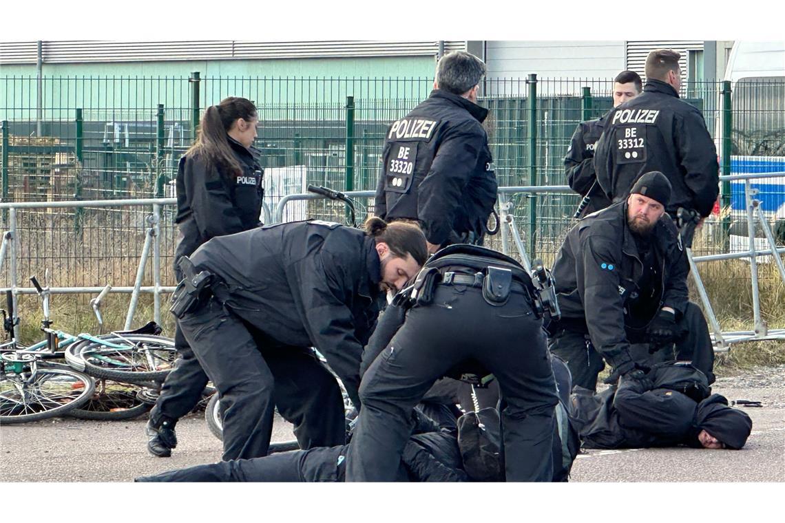 Polizisten halten Demonstranten am Boden fest. Sie hatten zuvor versucht mit Fahrrädern Richtung Veranstaltungshalle vorzudringen.