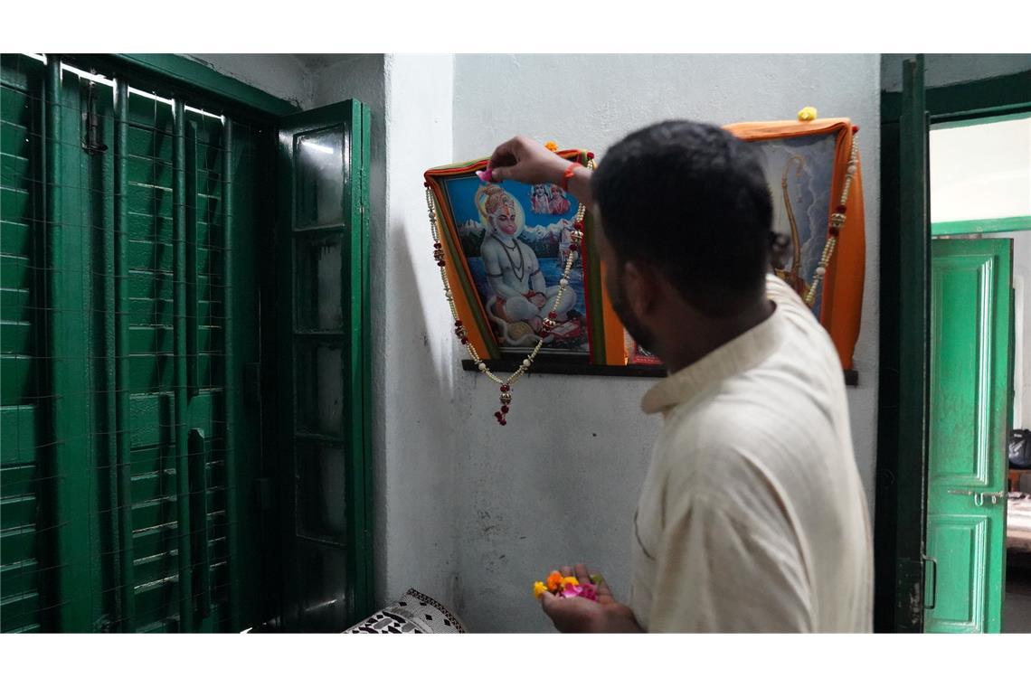 Priester Kalikant Dubey schmückt ein Bild von Gott Hanuman in seinem Büro.