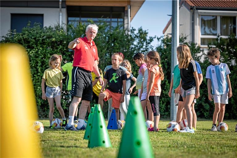 Rainer Dietrich erklärt den aufmerksamen Drittklässlern aus Großerlach, wie sie erst dribbeln und dann abziehen sollen. Foto: Alexander Becher