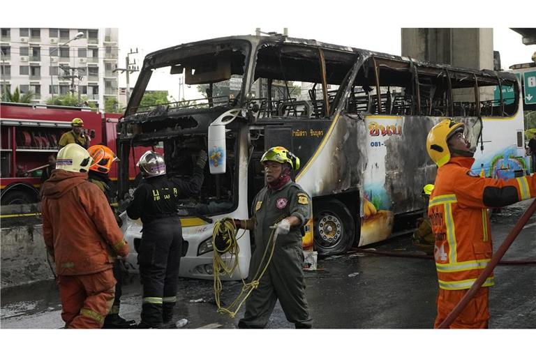 Rettungskräfte arbeiten in einem Vorort von Bangkok an der Stelle, an der ein Bus in Brand geraten war, in dem junge Schüler saßen.