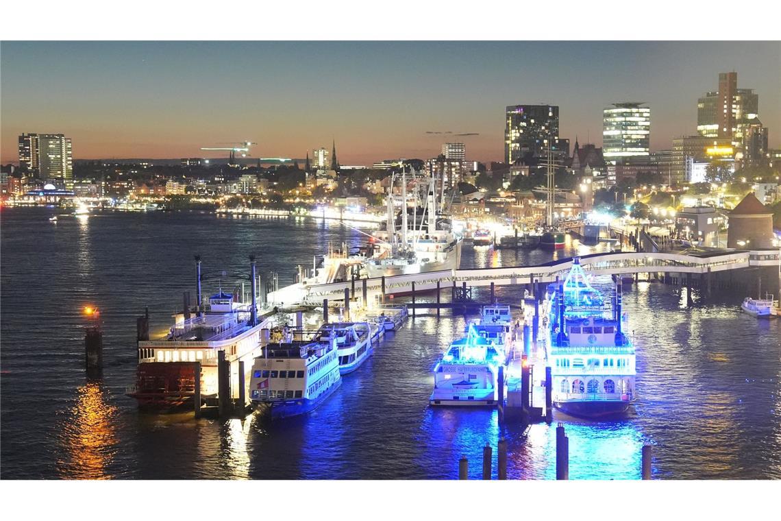 Schiffe und Gebäude leuchten im Hafen von Hamburg.