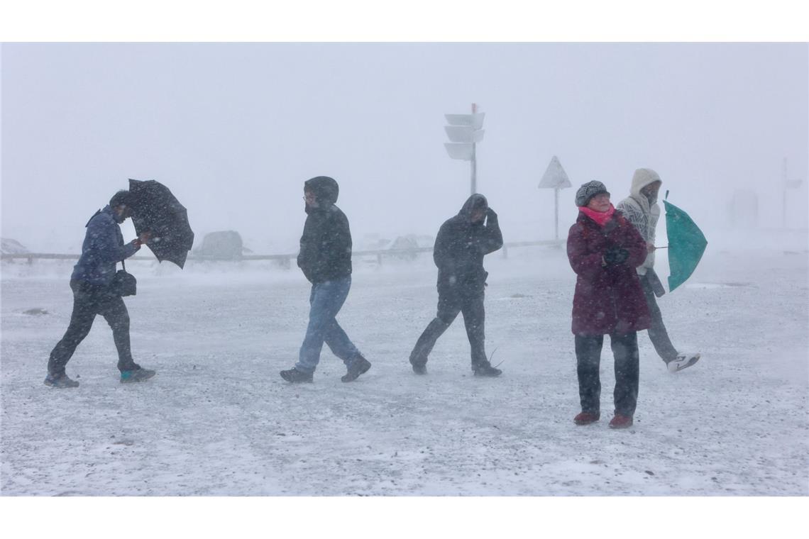 Schnee im Oberharz: Wanderer gehen bei frostigen Temperaturen und Wind auf dem Brocken entlang.