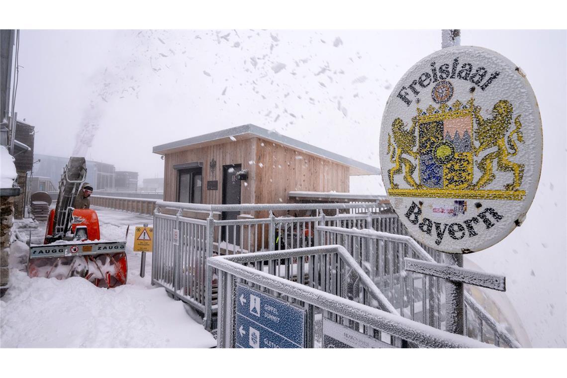 Schnee im Spätsommer: Auf der Zugspitze räumt eine Frau den Neuschnee weg