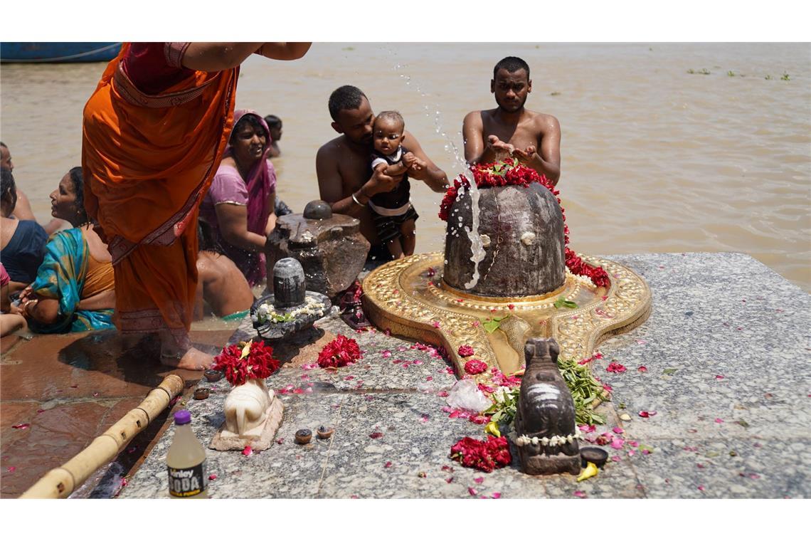 Sharmila und Familienangehörige baden neben einem Symbol von Gott Shiva im Ganges, nachdem sie dort auch die Asche ihrer Angehörigen versenkt haben.