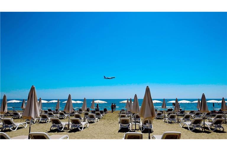 Sonne am Strand von Larnaka in Zypern. Im Hintergrund ein Flugzeug im Anflug auf den Flughafen.