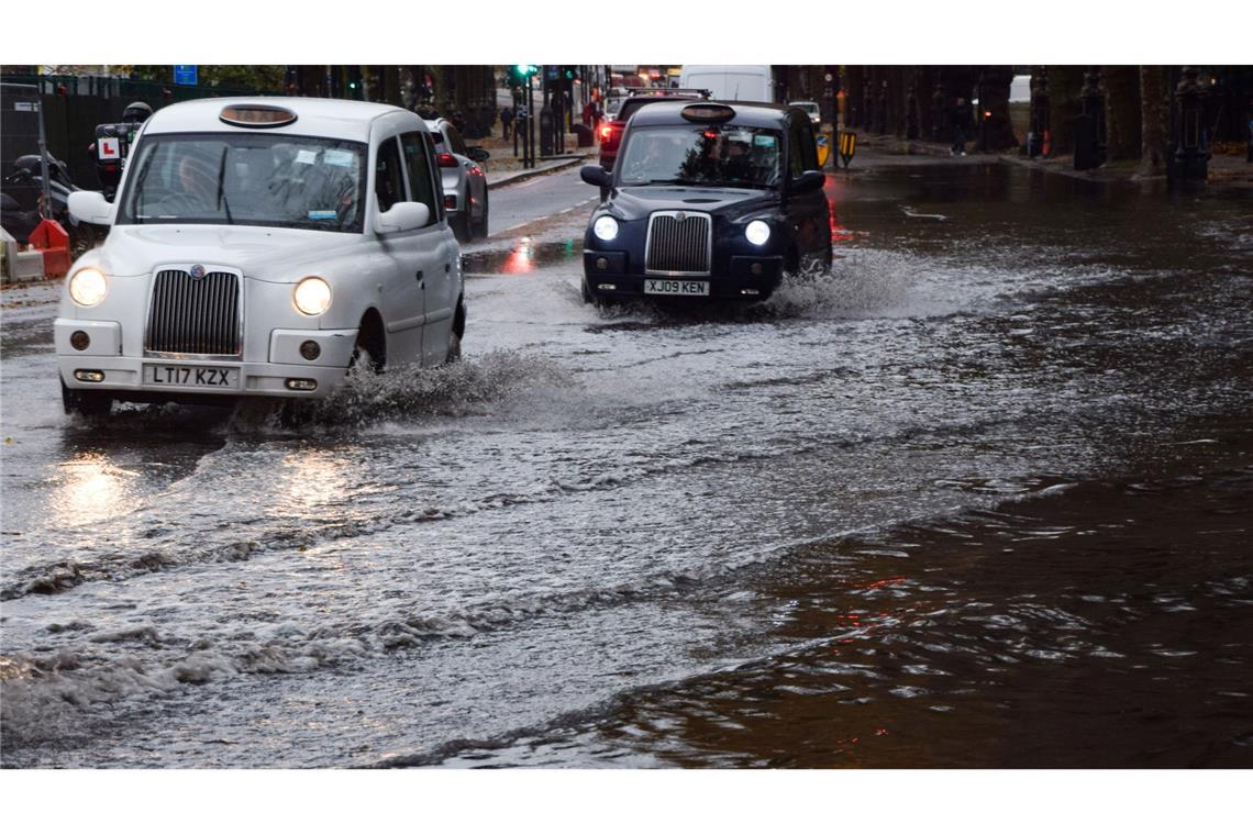 Taxis fahren über eine überschwemmte Straße in London.