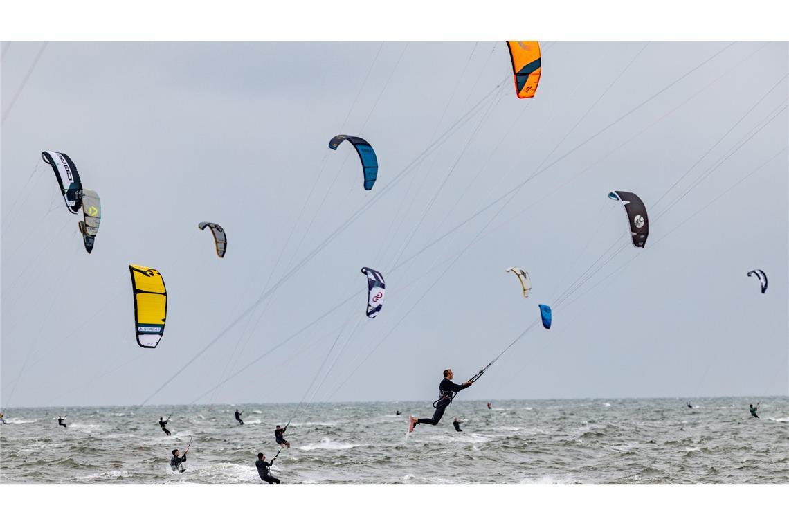 Teilnehmer der California Kitesurf Masters trotzen dem heftigen Regen und gleiten auf ihren Boards am Strand von St. Peter-Ording über das Wasser.