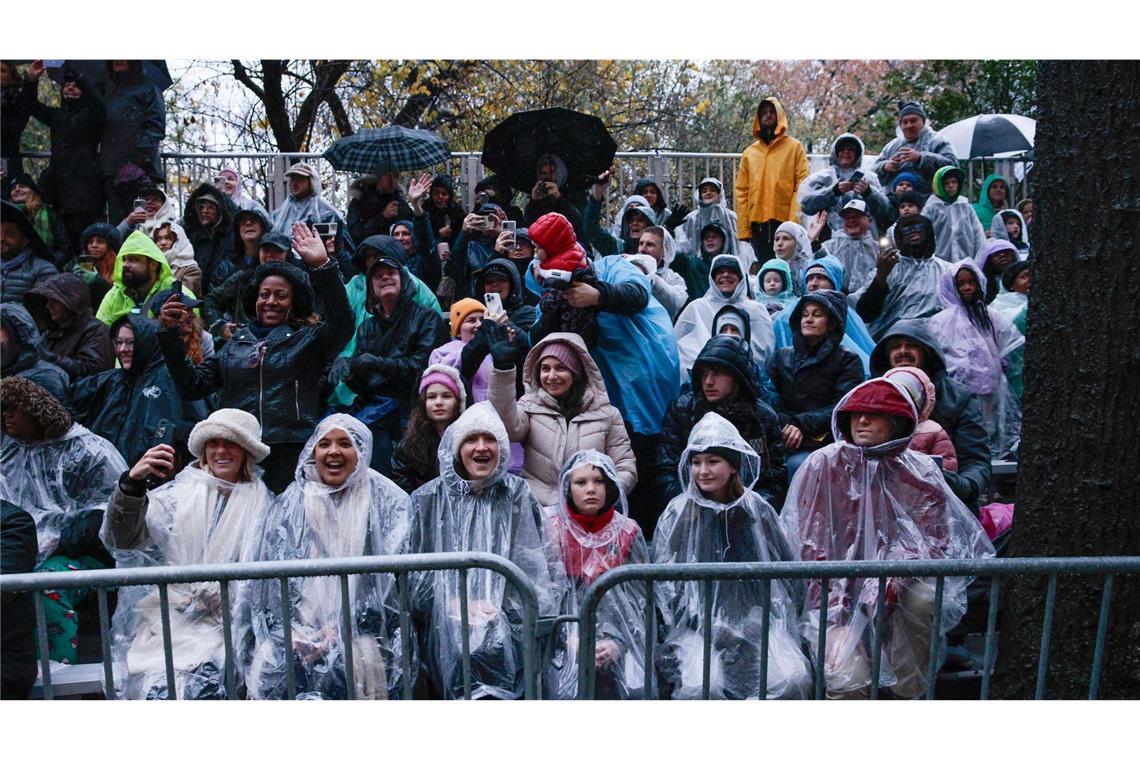 Trotz des Regens stehen viele Menschen an der Strecke der Thanksgiving Day Parade.