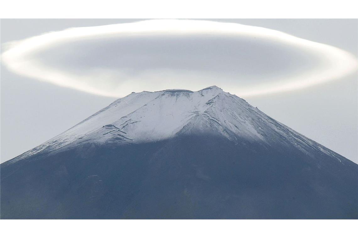 Über der schneebedeckten Spitze des Fuji ist eine ringförmige Wolke.