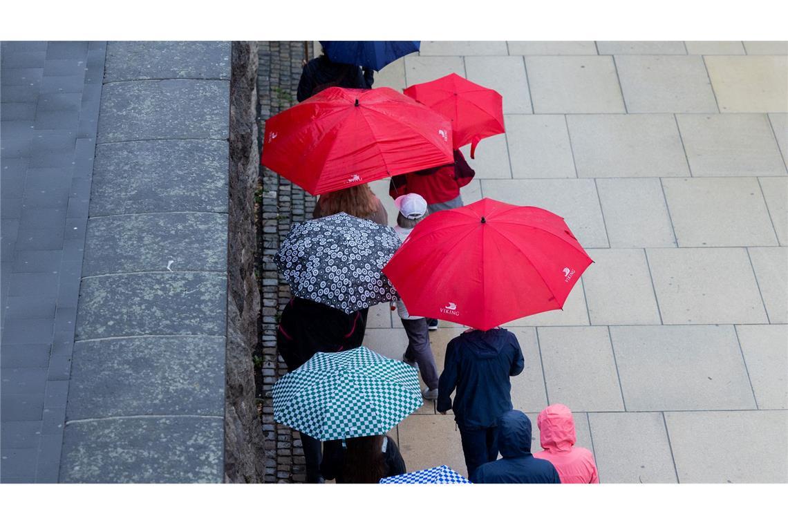 Viele bunte Schirme: Eine Touristengruppe geht bei Regen gut beschirmt auf dem Rheinboulevard in Köln entlang.