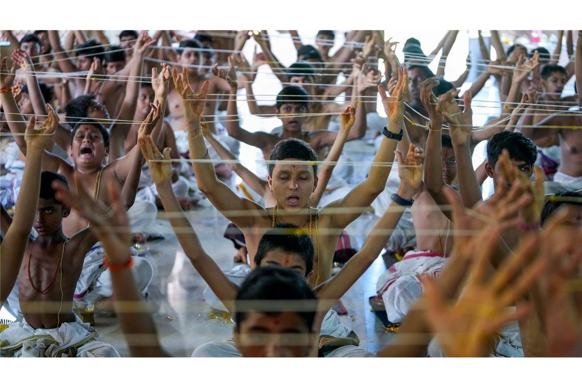 Während einer Zeremonie zum Raksha-Bandhan-Festival führen Schüler einer indischen Schule Rituale mit heiligen Fäden, genannt Janoi, durch, die sie quer über ihren Köpfen halten.